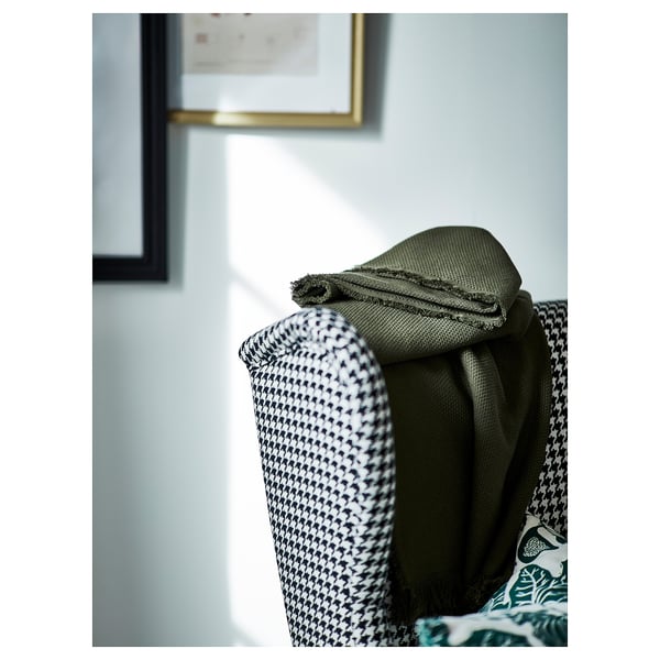 Luxurious green fabric draped over stylish houndstooth-patterned chair, emphasising comfort and high-quality design.