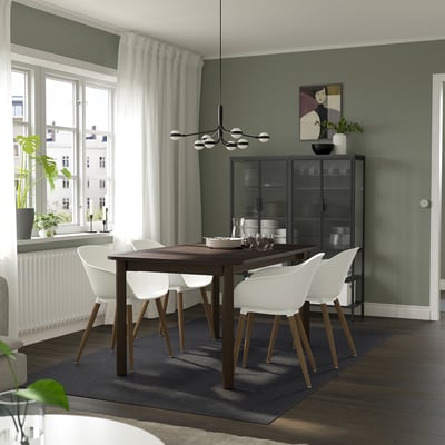 Modern dining area with STRANDTORP extendable table, dark wood and white chairs, green walls, and large window.