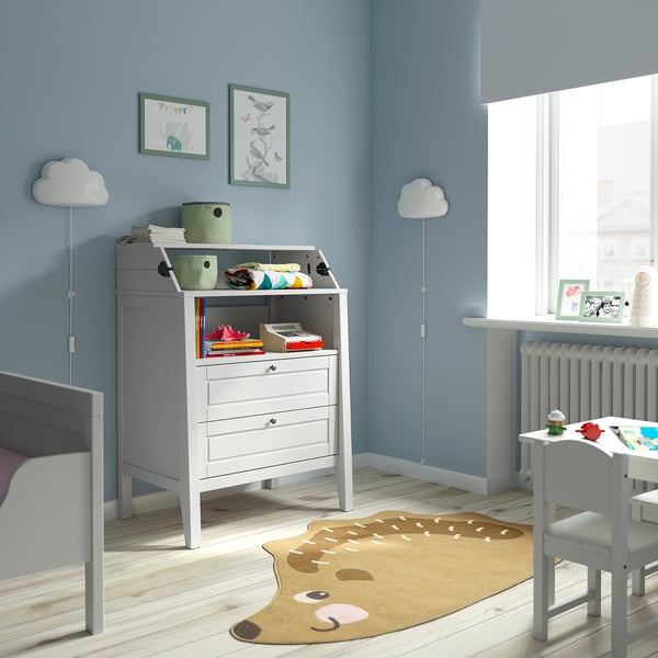 Childs room with SUNDVIK changing table, blue walls, bear rug, cloud lamps, bookshelf, and bed.