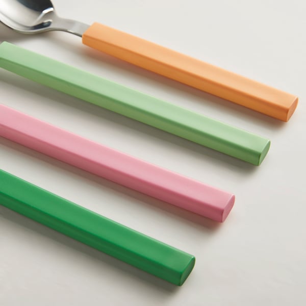 Colourful cutlery set: orange, green, pink handles, neatly arranged on white surface.