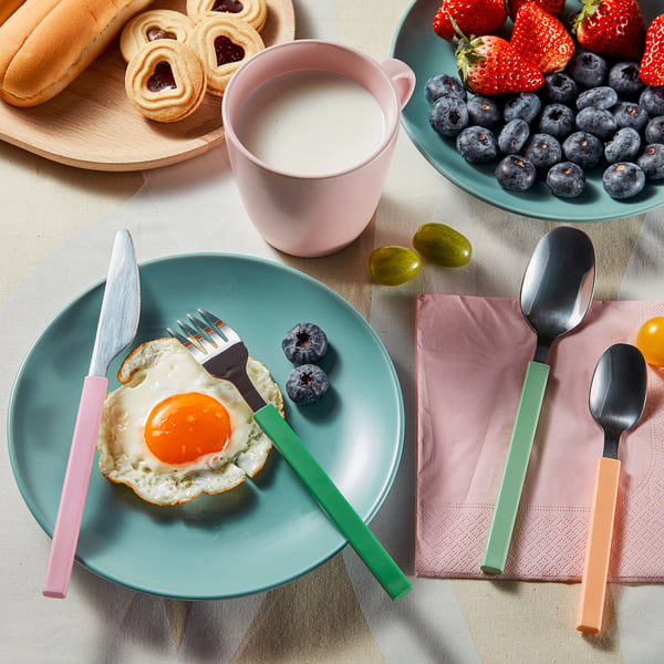 Colourful cutlery set with plates, berries, and breakfast. Bright handles enhance table settings mood.