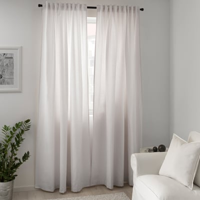 Modern minimalist room with sheer TIBAST curtains, white armchair, and plant.