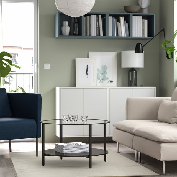 Green living room with TIDTABELL table, vases, beige rug, white sofa, navy chair, and books.