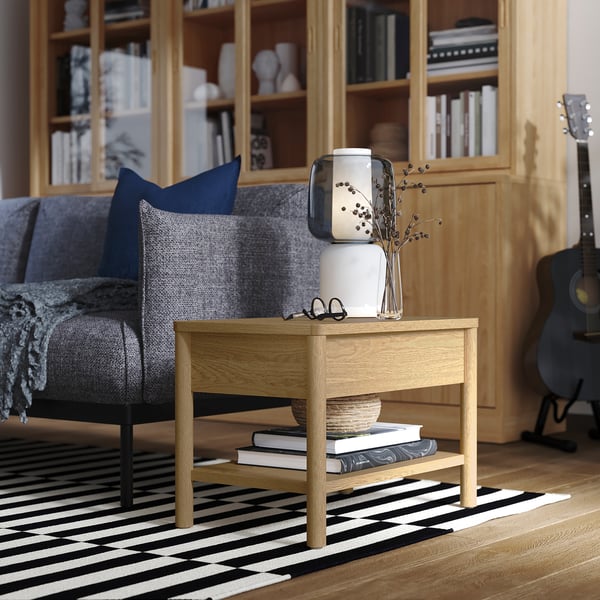 Cosy living room with grey sofa, side table, books, and guitar.