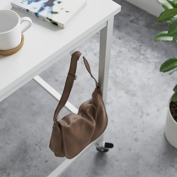 Brown leather bag hangs from white wooden meeting table with castors, featuring hooks for convenience.