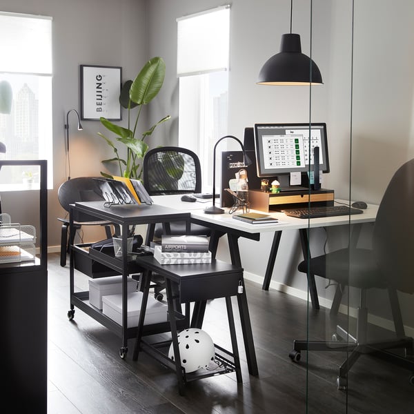 Modern office setup with TROTTEN black trolley providing workspace and storage, positioned neatly under desk.