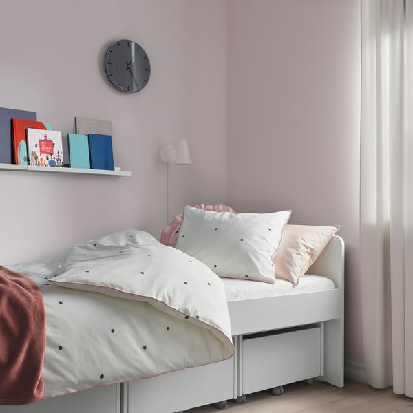 Bedroom with VÄNKRETS dot duvet & pillows in pink. White bed, clock, light curtains.