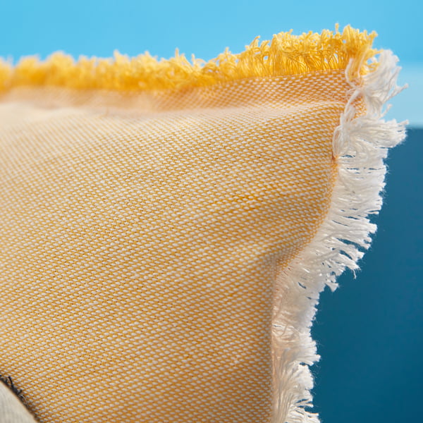 Close-up of VÄXELBRUK cushion cover with yellow-white woven fabric and zip along one edge.