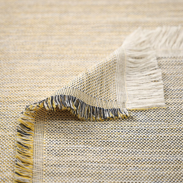 Woven throw with yellow, blue, and grey fringes, draped on beige textile.