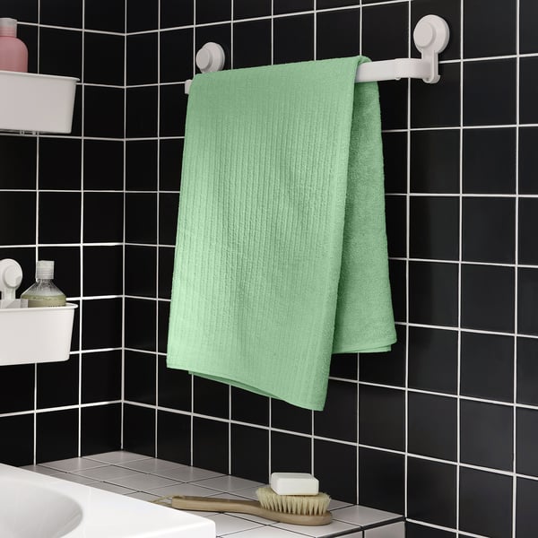 Mint green towel on white rack against black tiles.