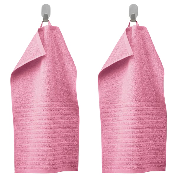 Two pink VÅGSJÖN towels hang side by side on metal hooks, featuring a soft textured design and vibrant colour.
