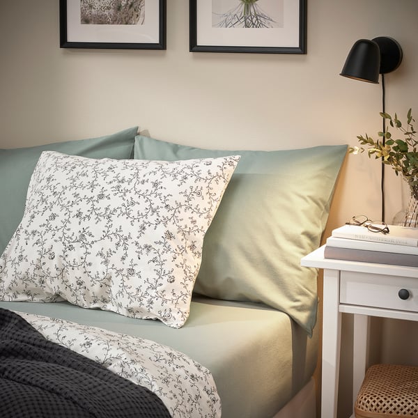 Bed with greenish sheets, VÅRVIAL, soft cotton. Simple floral print, neat against wall.