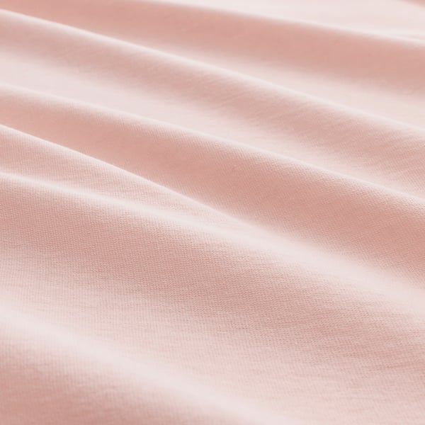 Close-up of soft, pinkish-red cotton fabric, smooth texture, slightly crinkled folds.