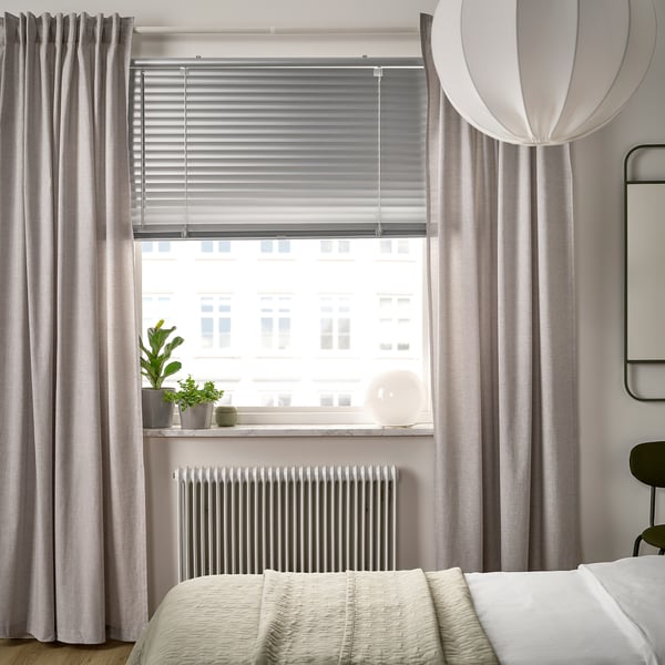 Venetian blinds on large window, curtains, bed, plants, pendant light.