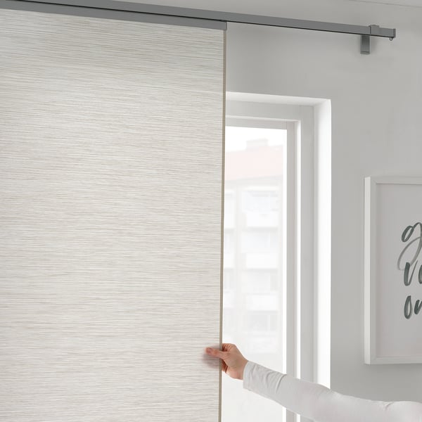 A hand adjusting VIDGA curtain panel holder, demonstrating easy curtain adjustments.