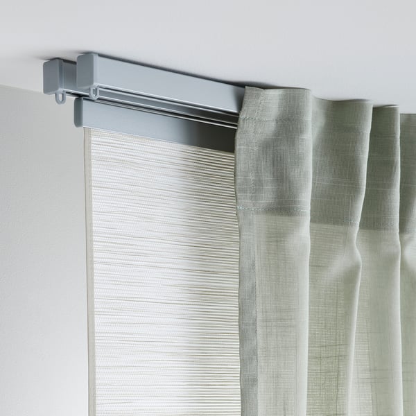 Grey curtain rail mounted on white wall, supporting light green curtains. Easy to assemble and flexible for tricky spaces.