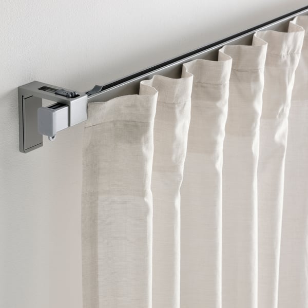 Beige curtains hang on a VIDGA rail using wall fittings to block light.