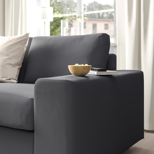 Dark grey VIMLE sofa armrest holds a wooden bowl with lemons and a magazine near a window.