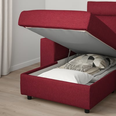 Red sofa bed with storage and headrest, showing an open storage compartment with pillows inside.