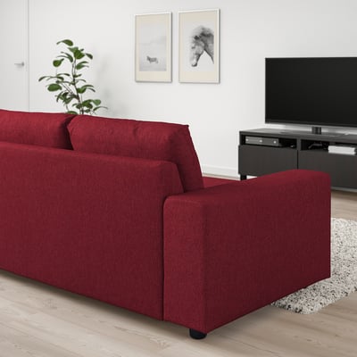 Modern living room with red VIMLE sofa, flat screen tv, plant, rug, and framed art. Sofa is wide and deep, ideal for relaxation.
