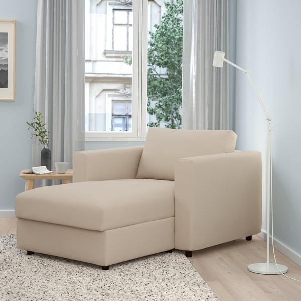 Beige VIMLE chaise lounge, with backrest against wall, next to tall white lamp, small wood table, and large window.