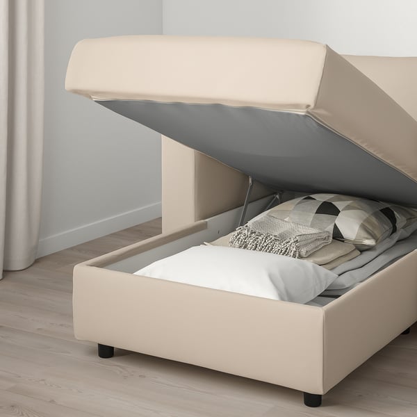 Beige sofa with open storage, cushions, and blanket inside.