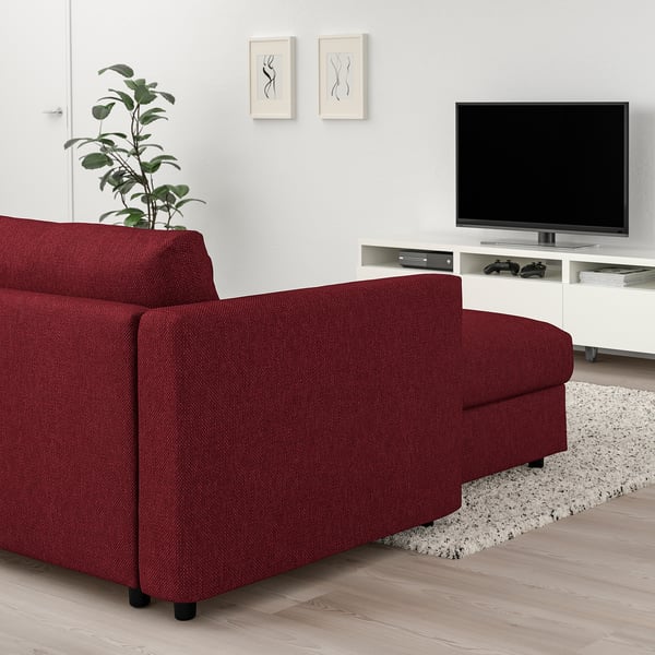 Cosy living room with large red VIMLE sectional sofa against white wall, flat-screen tv on stand, stylish plant, and rug.