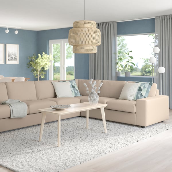 Modern living room with VIMLE sofa, coffee table, grey curtains. Natural light, cosy decor, blue/white pillows, rug, pendant lamp, plants.