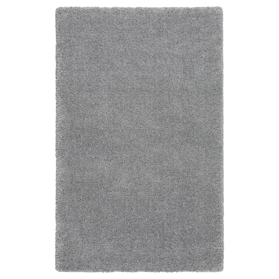 A grey shaggy area rug, rectangular, with varying yarn textures, providing softness and sound dampening.
