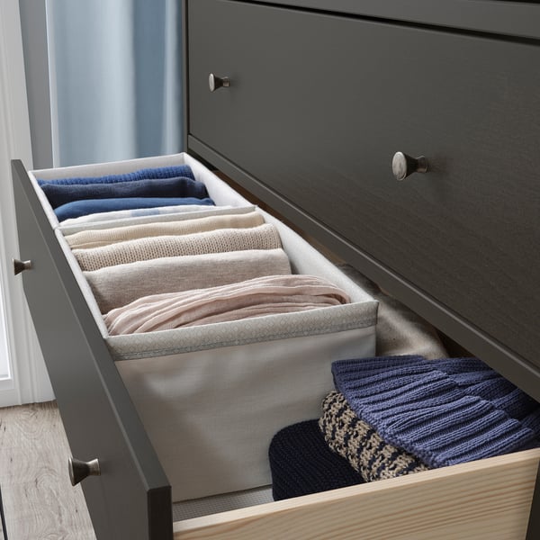Organiseret skuffe med BAXNA stofopbevaring i blå og beige, der pænt opbevarer t-shirts og håndklæder i en grå kommode.