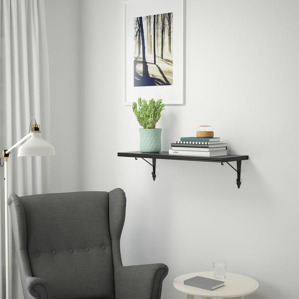 Hyggeligt hjørne med stol, bøger, plante, lampe og skovprint.
