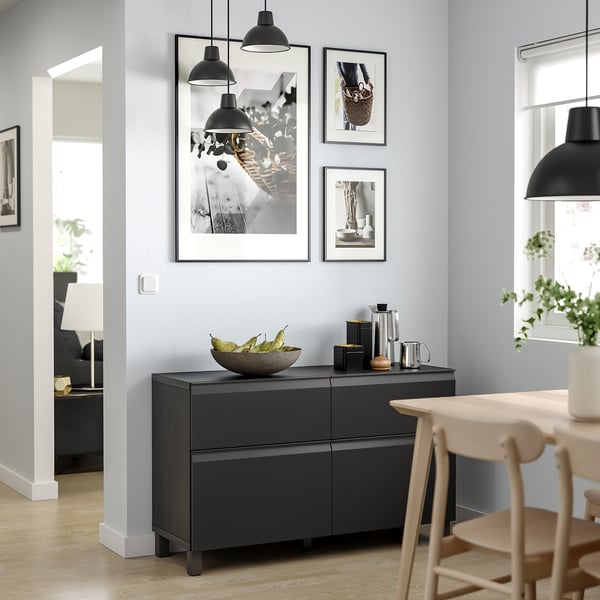 Moderne spisestue med sort BESTÅ-skænk, pendler og træstole. Væggen viser indrammet kunst.