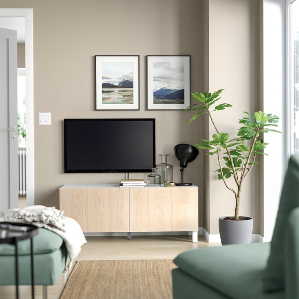 Moderne minimalistisk stue et lyst træ-tv-bord med fladskærm, to naturprints, en grøn plante og en blågrøn stol.