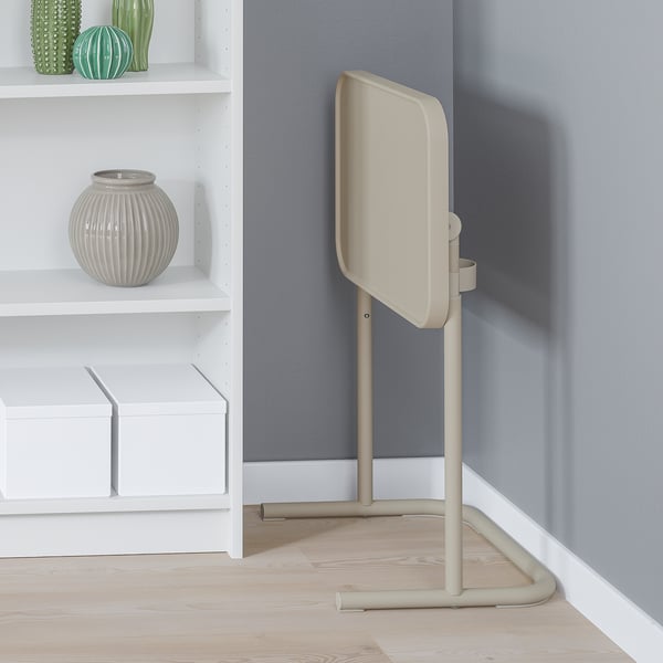 Beige laptopstativ ved siden af hylden, vippet for behageligt arbejde.