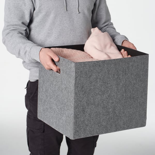Person, der holder en grå filtkasse med håndtag, designet til at passe til kallax-hylder.