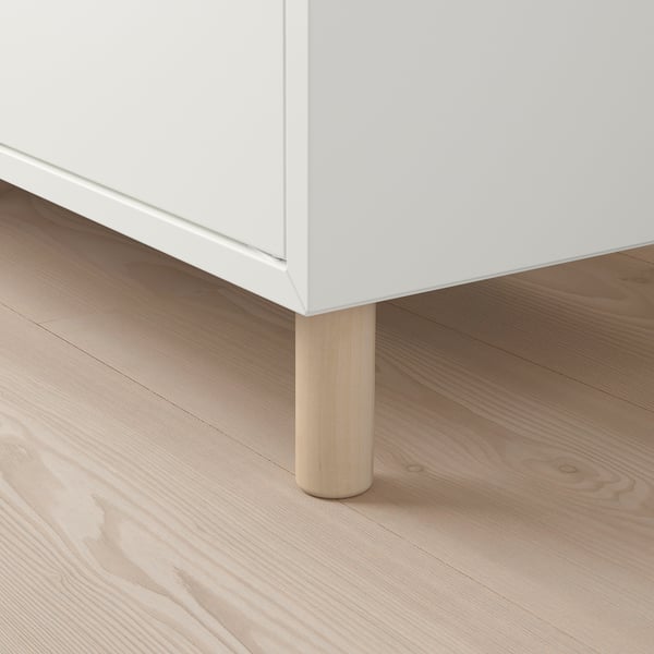 Hvide møbler med lyse træben på trægulv. Robust design, let hævet fra jorden.