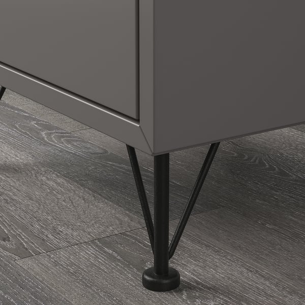 Mørkegrå opbevaringsmøbel på trægulv med slanke sorte metalben for stabilitet og slankt design.