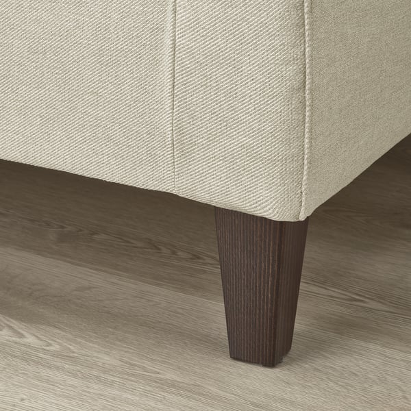 En moderne sofa med tilspidsede træben og polstret tekstureret stof.