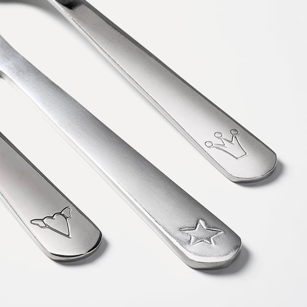 Tre børneredskaber i rustfrit stål: kniv, gaffel, ske, hver med unikke indgraverede designs.