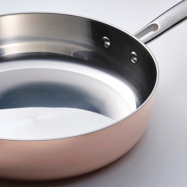 Sauteringspande af høj kvalitet med poleret rustfrit stål inderside og afrundet håndtag, der reflekterer lys og er designet til jævn varmefordeling.