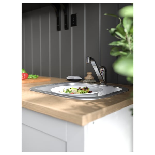 Moderne køkkenvask med håndvask i rustfrit stål, bordplade i træ og vandhane i krom.