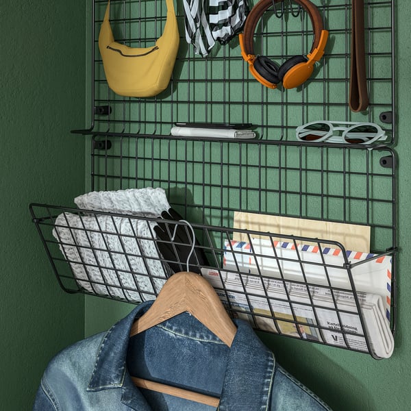 Metalvægorganisator med hængende ting: gul taske, hovedtelefoner, solbriller, breve, lommetørklæder og denimjakke.