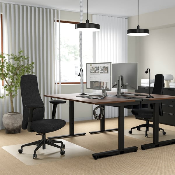 Moderne kontor med 2 ergonomiske stole, justerbare skriveborde, dobbelte skærme, pendellamper og store vinduer.