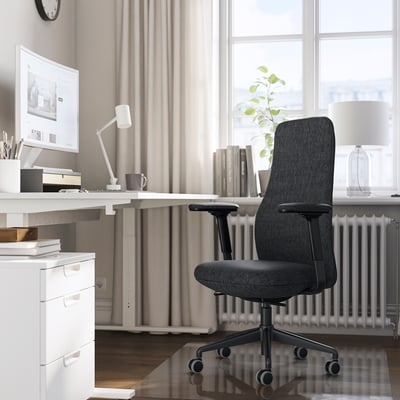 Hjemmekontor med GRÖNFJÄLL mørkegrå ergonomisk stol, hvidt skrivebord og computer. Stolen passer pænt under skrivebordet, med justerbar for komfort.