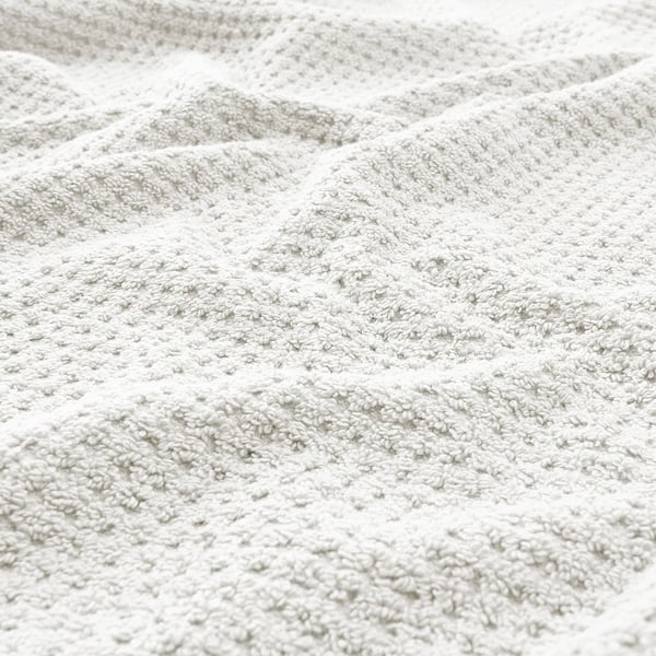 Blødt, blødt beige håndklæde med synlige, tætvævede løkker, der antyder høj kvalitet og sugeevne.