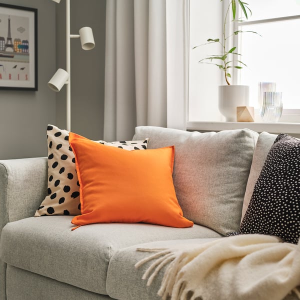 Grå sofa med lyse orange GURLI-puder - en solid, en prikket.