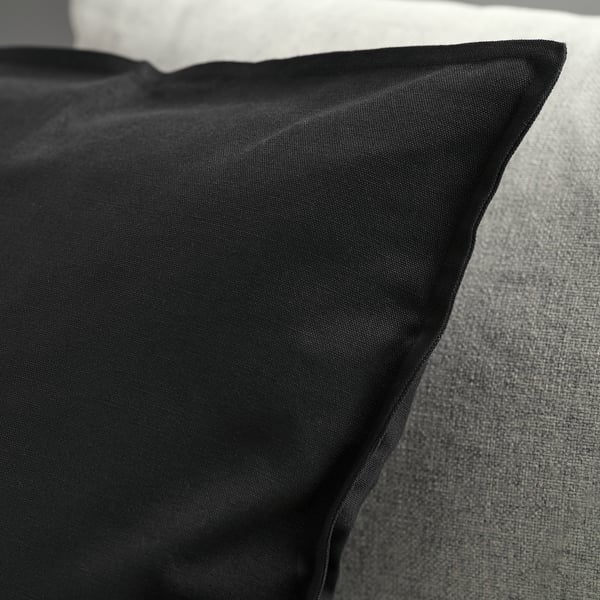 Sort pudebetræk på grå sofa, glat tekstur, lynlås synlig.