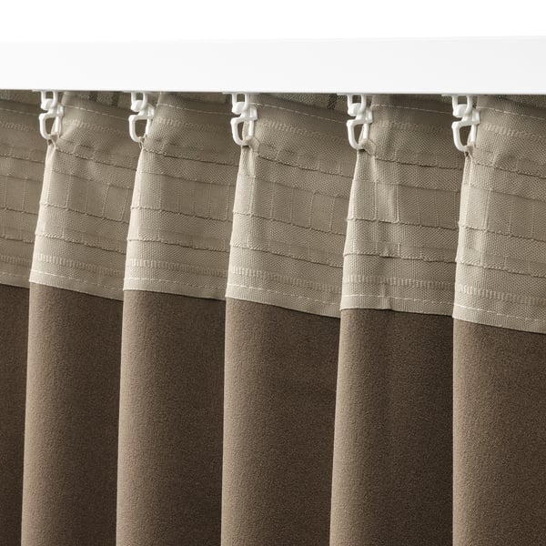 Et nærbillede af beige gardiner med et skotskternet mønster forbundet med plastikkroge. Disse gardiner er designet til at mørklægge rummet og give privatliv.