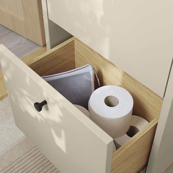 Åbent skab med to ruller toiletpapir og en netpose, der viser organiseret opbevaring.