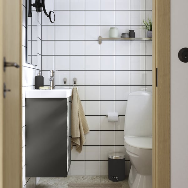 Minimalistisk badeværelse med mørkegrå HAVBÄCK forfængelighed, hvide fliser og sort tilbehør.